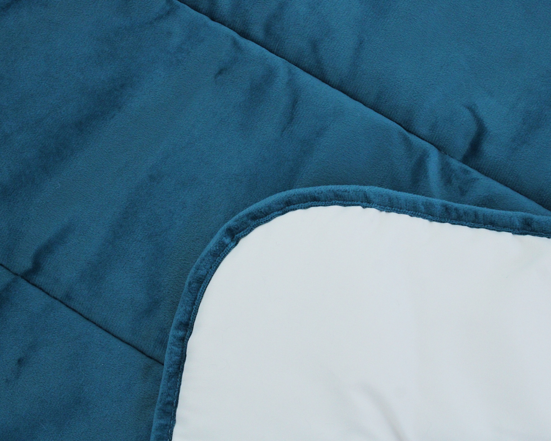 Colcha acolchoada azul com lado branco e bordas arredondadas