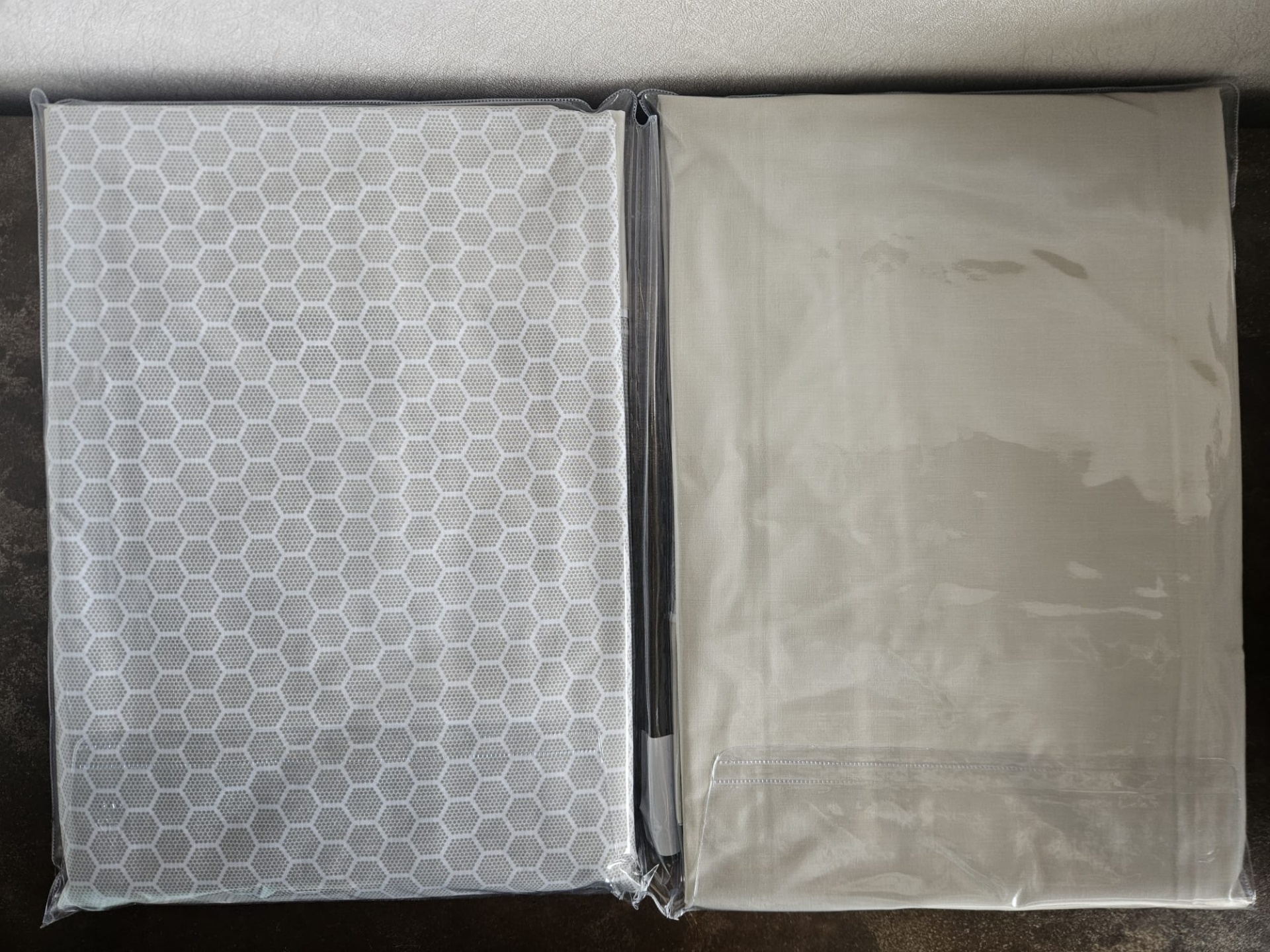 Duas capas de tecido embaladas, uma com padrão de hexágonos e outra lisa cinza claro
