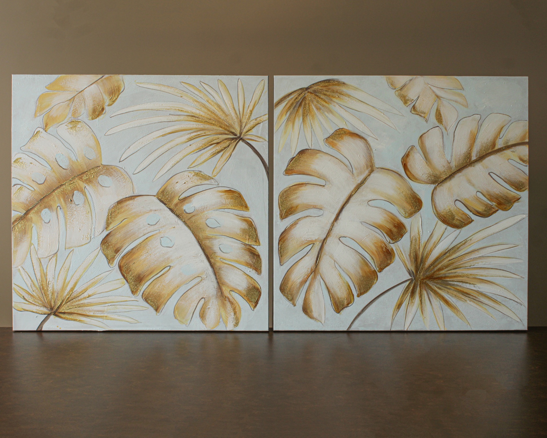 Dois quadros decorativos com folhas tropicais douradas e bege em fundo branco