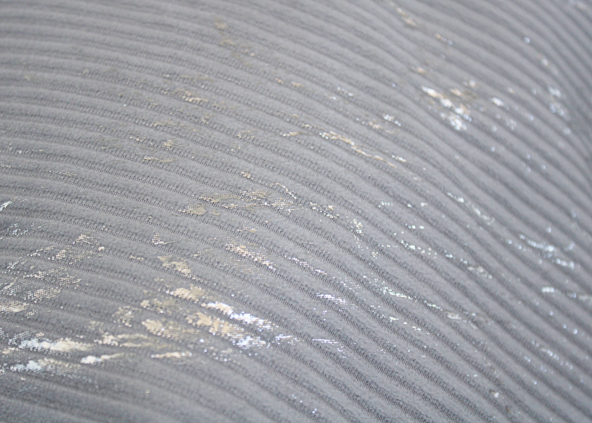Tecido cinzento com textura de riscas e manchas prateadas