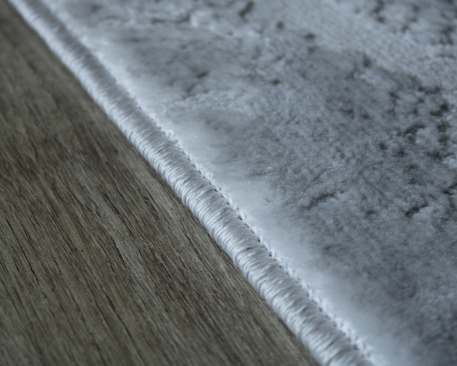 Close-up borda tapete cinza claro textura aveludada piso madeira clara