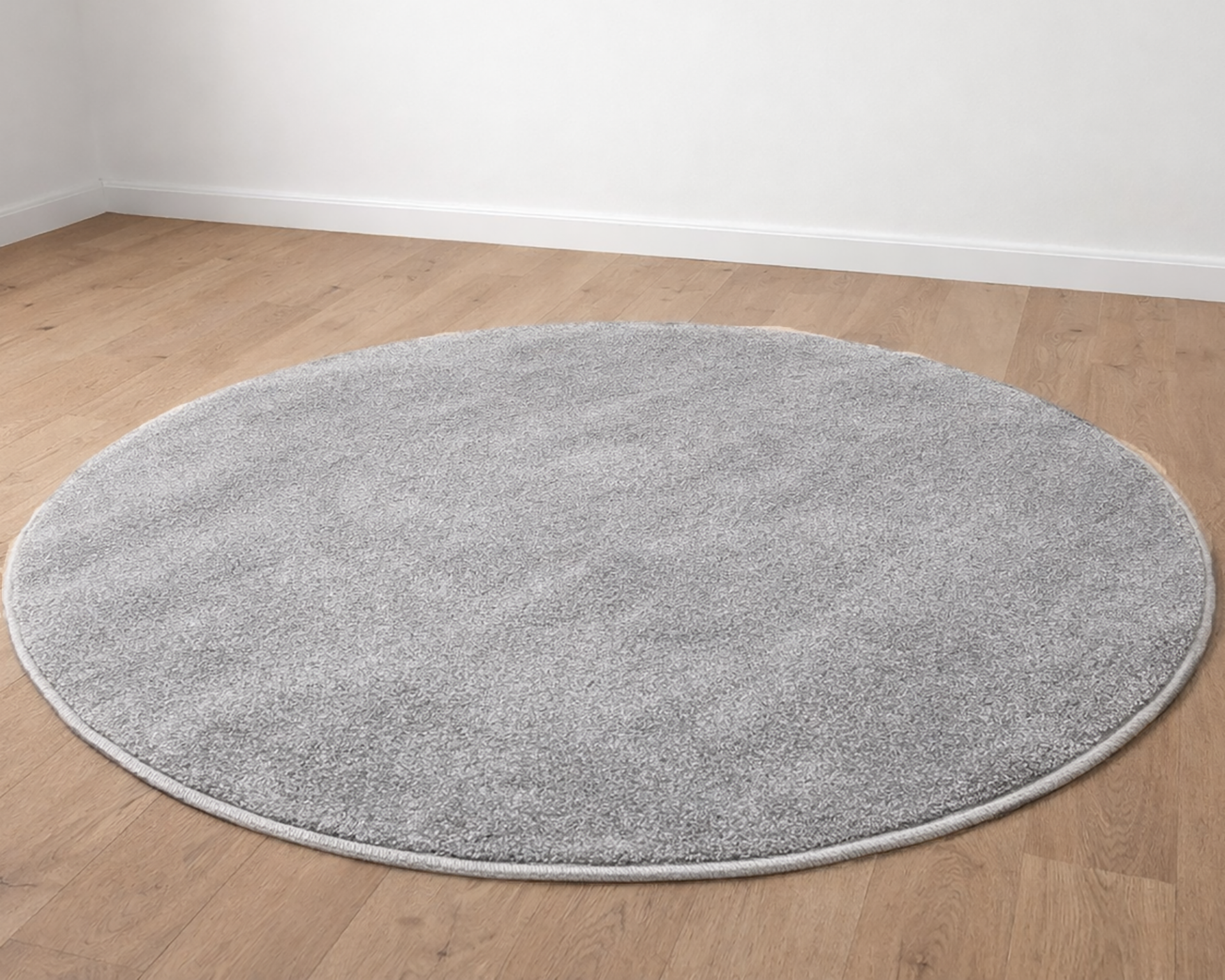 Tapete redondo cinza claro felpudo sobre chão de madeira clara
