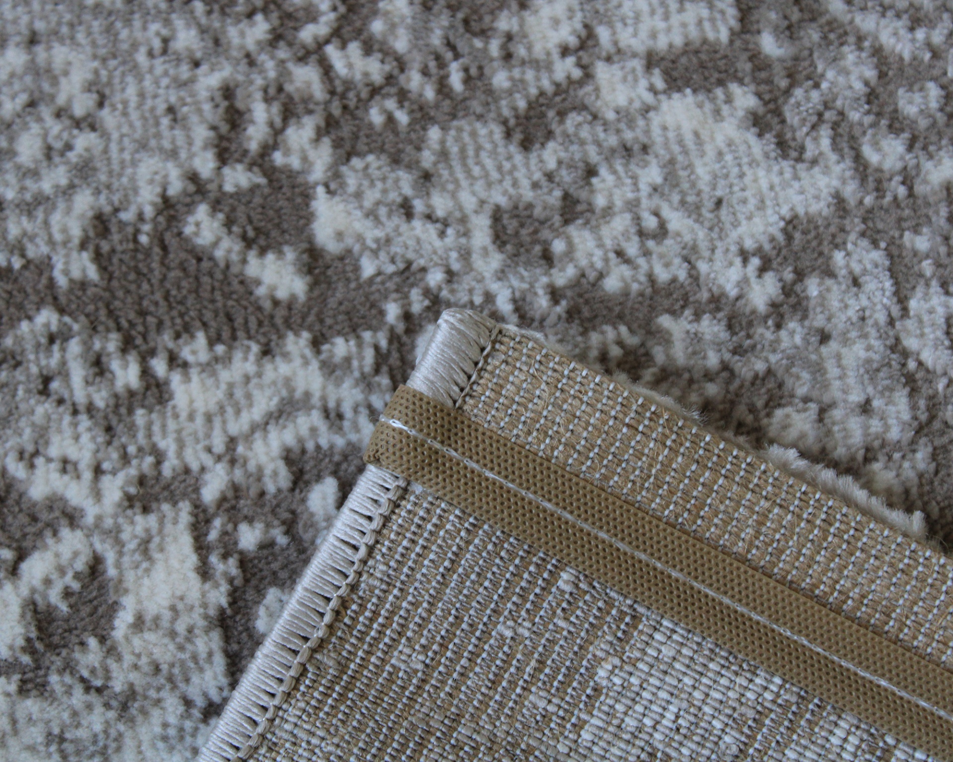 Tapete bege e castanho com padrão abstrato e canto dobrado com borda