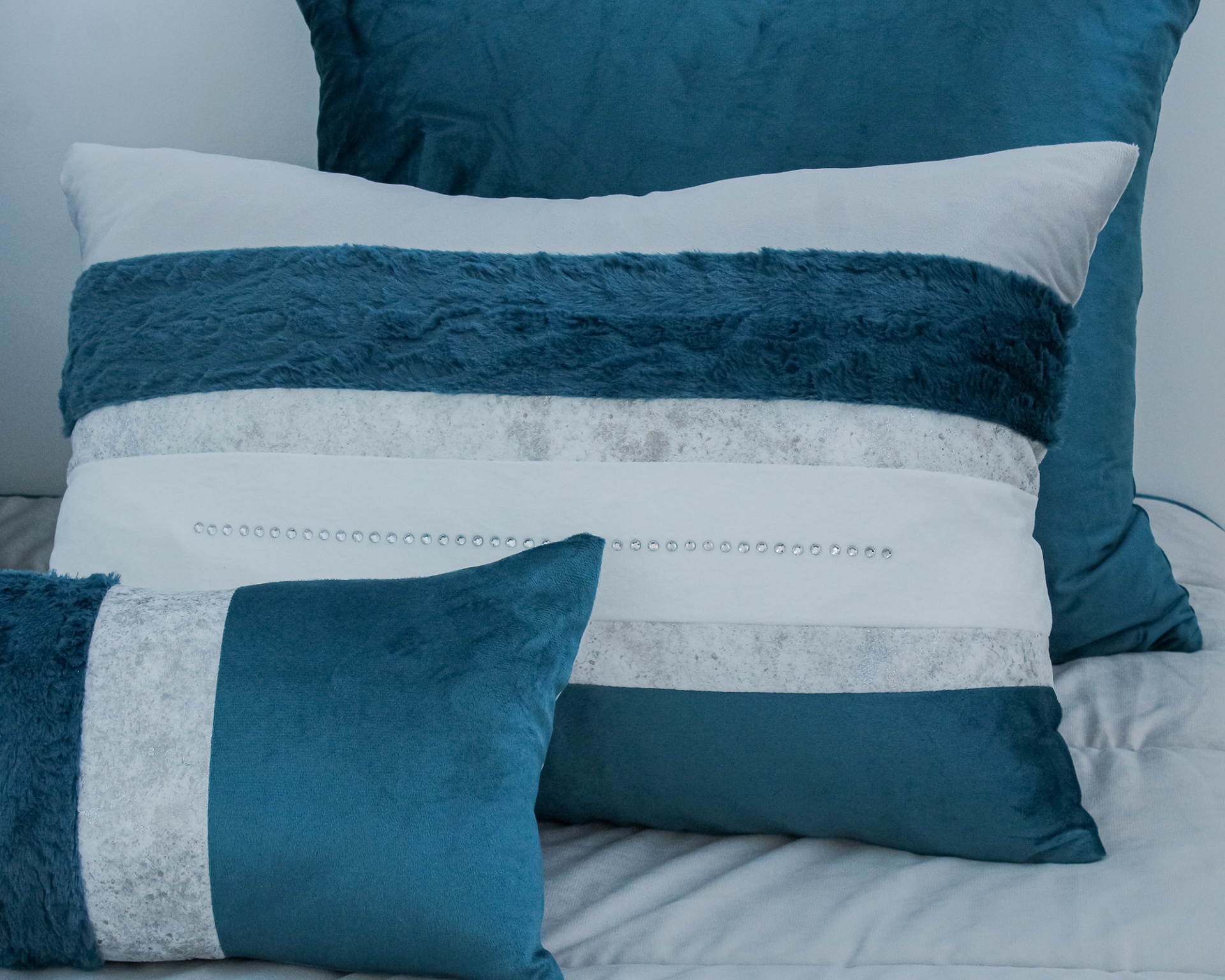 Três almofadas decorativas azuis e brancas sobre uma cama