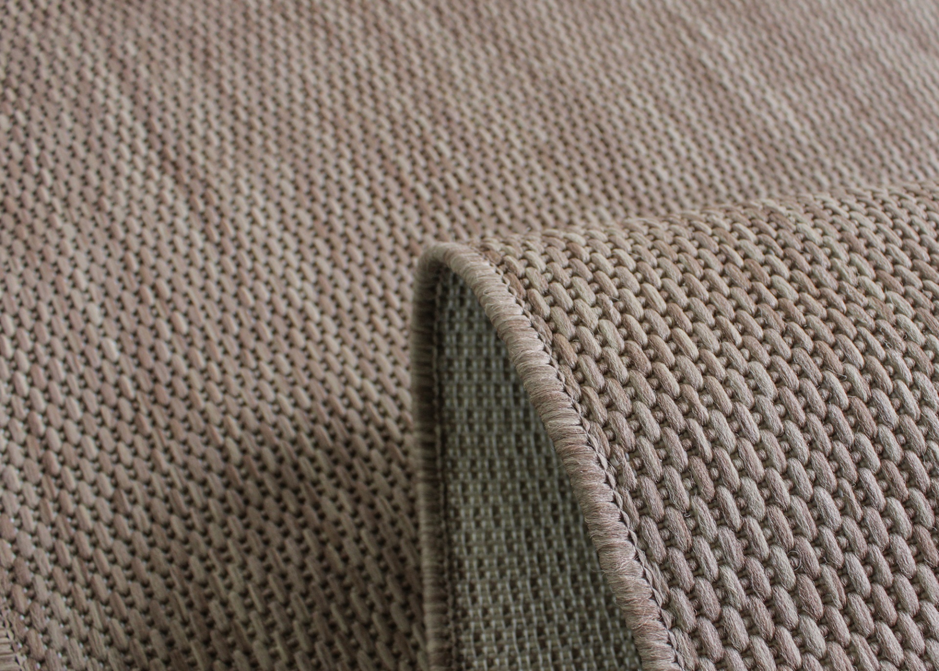 Tapete castanho-bege com padrão tecido e borda curvada para cima