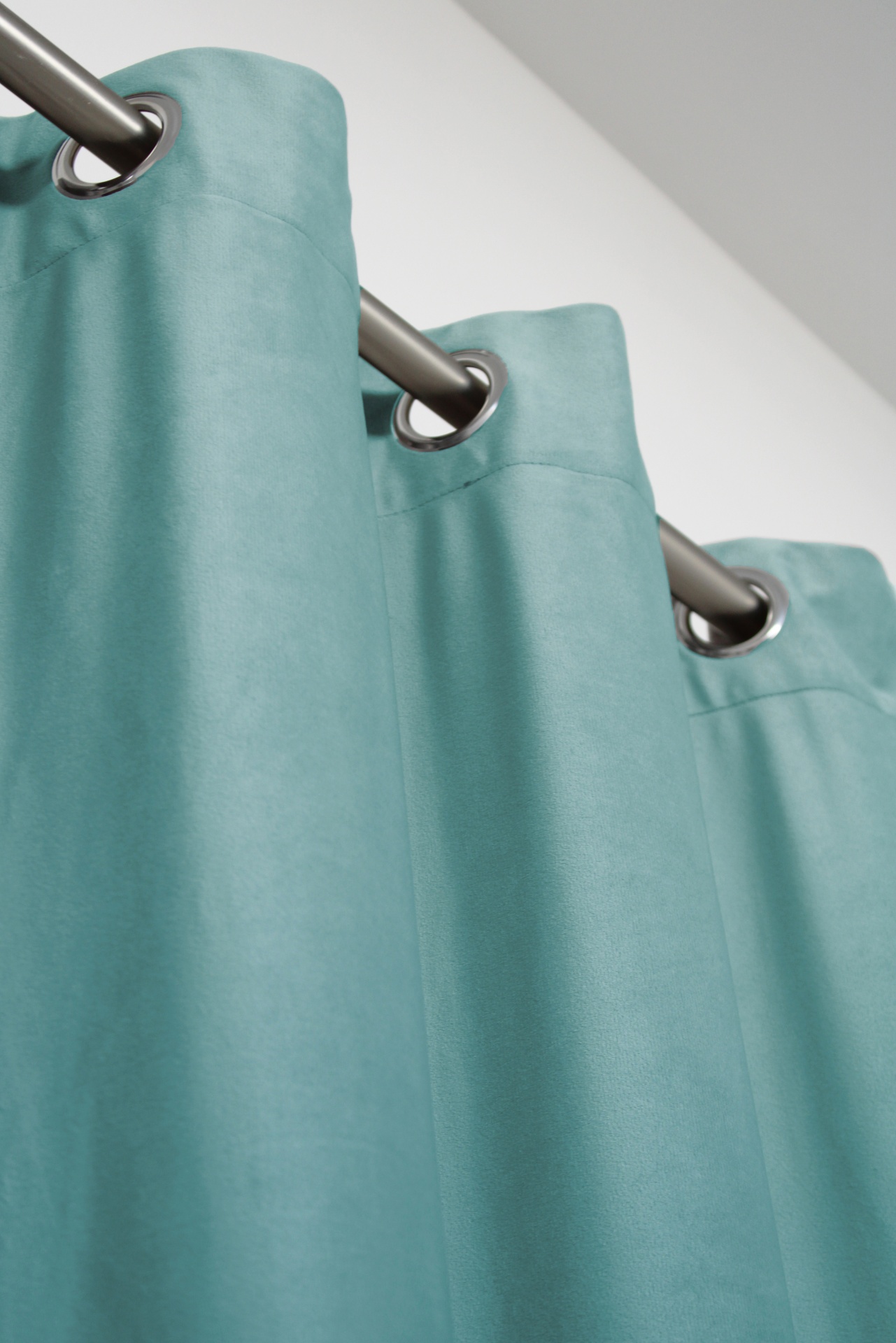 Cortina azul turquesa com ilhós metálicos numa barra prateada