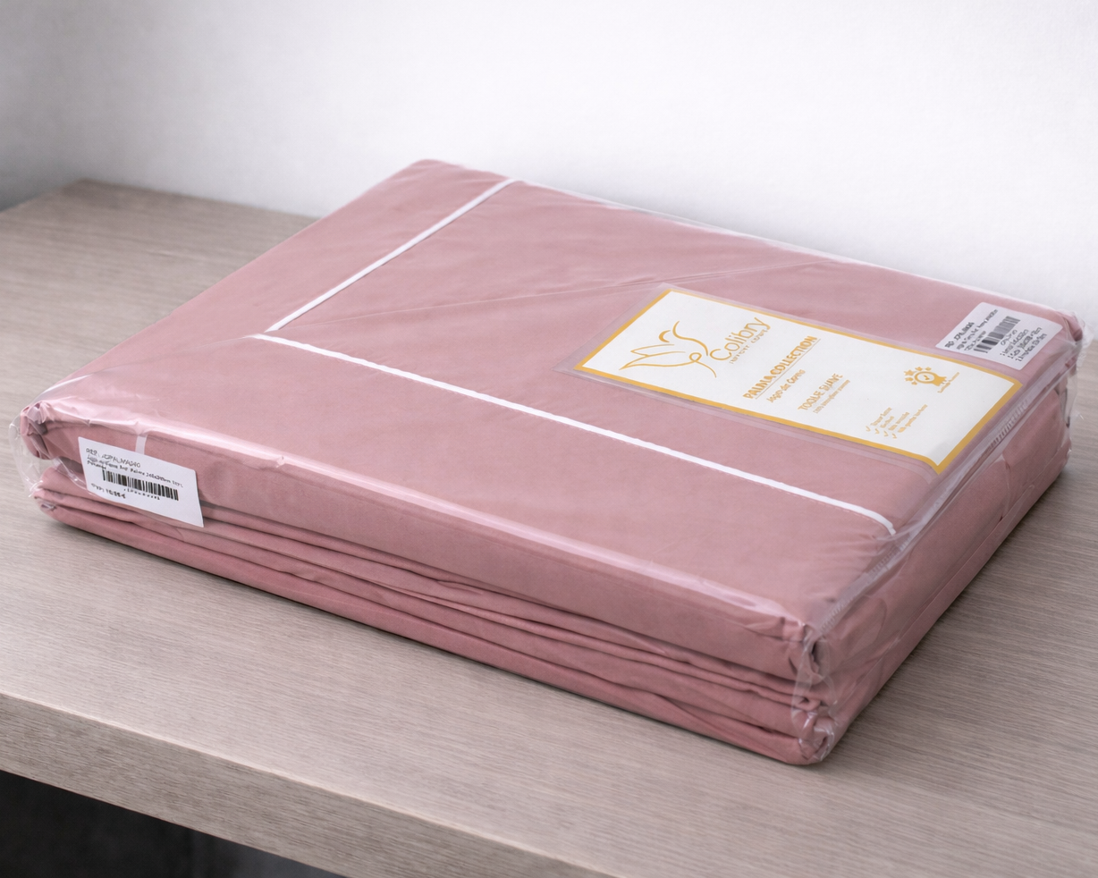 Lençol rosa embalado em plástico transparente com etiqueta Coilbry na mesa