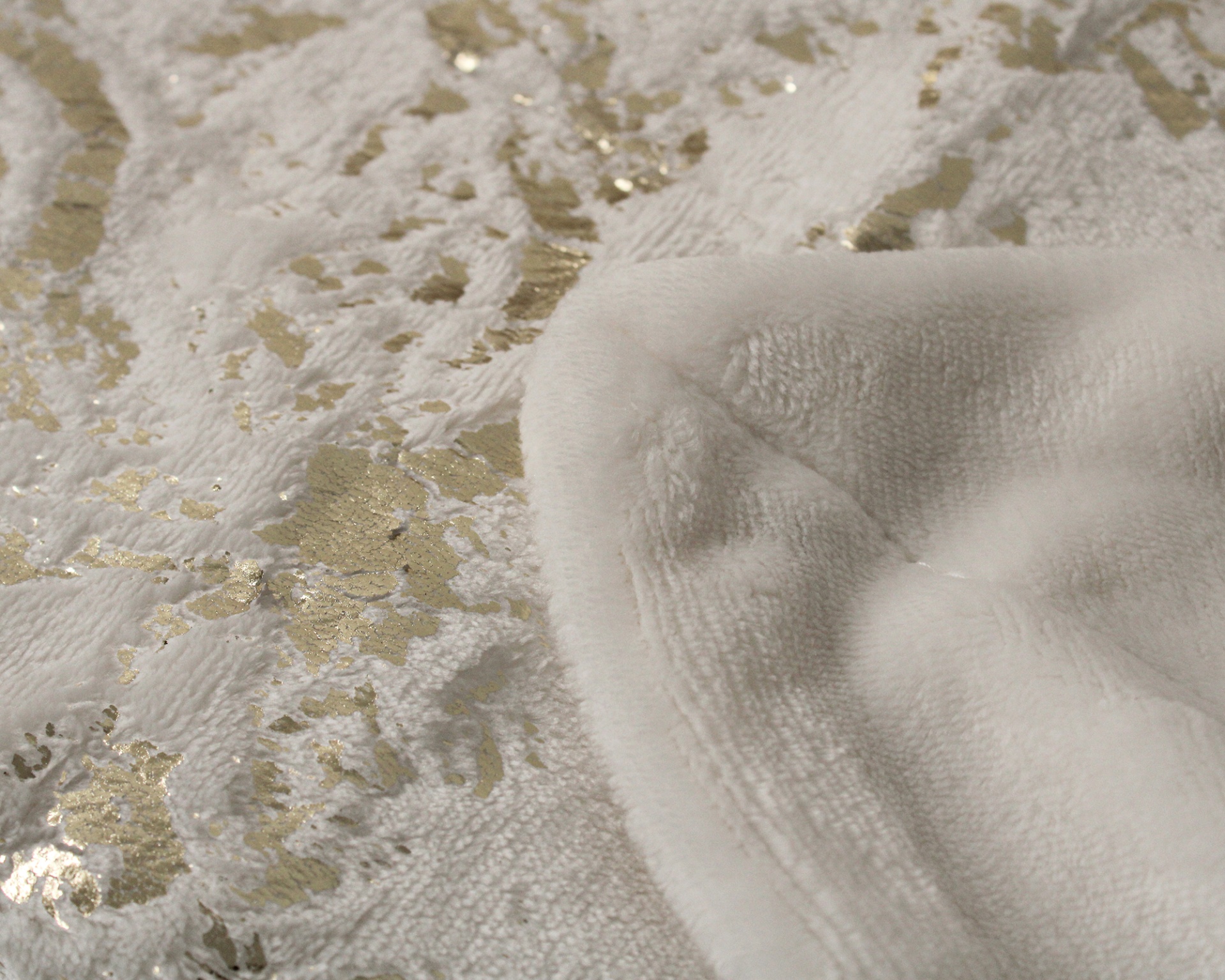 Toalha branca com padrão dourado e textura felpuda