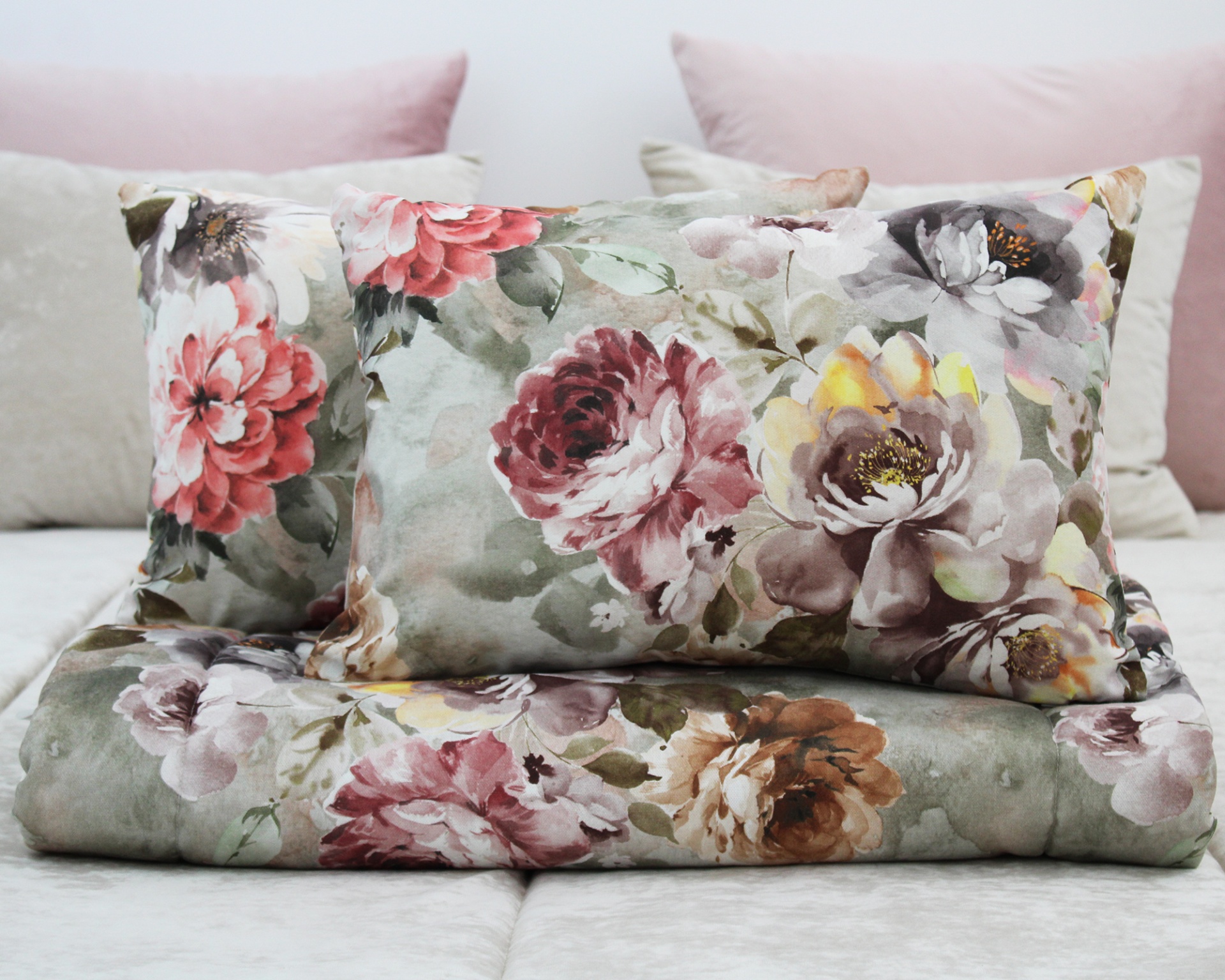 Edredão e almofada com padrão floral colorido sobre cama com almofadas cor de rosa e bege