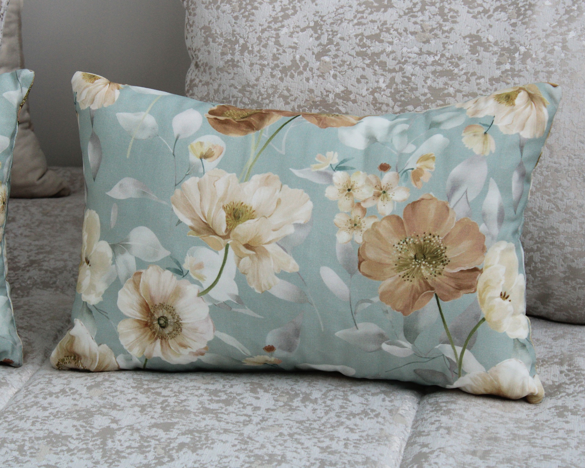 Almofada floral azul claro sobre superfície estofada cinza claro