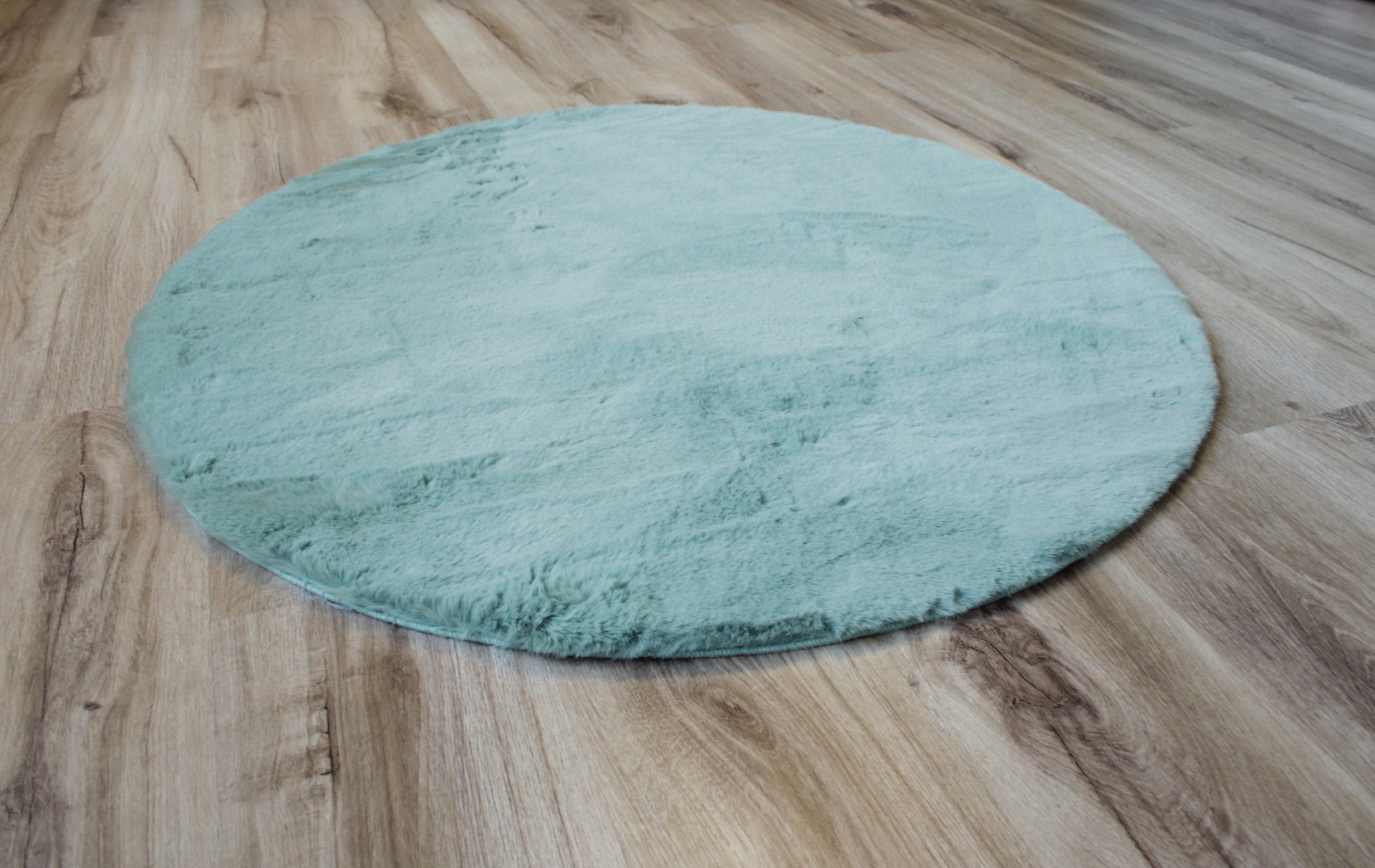 Tapete redondo azul claro sobre pavimento de madeira clara