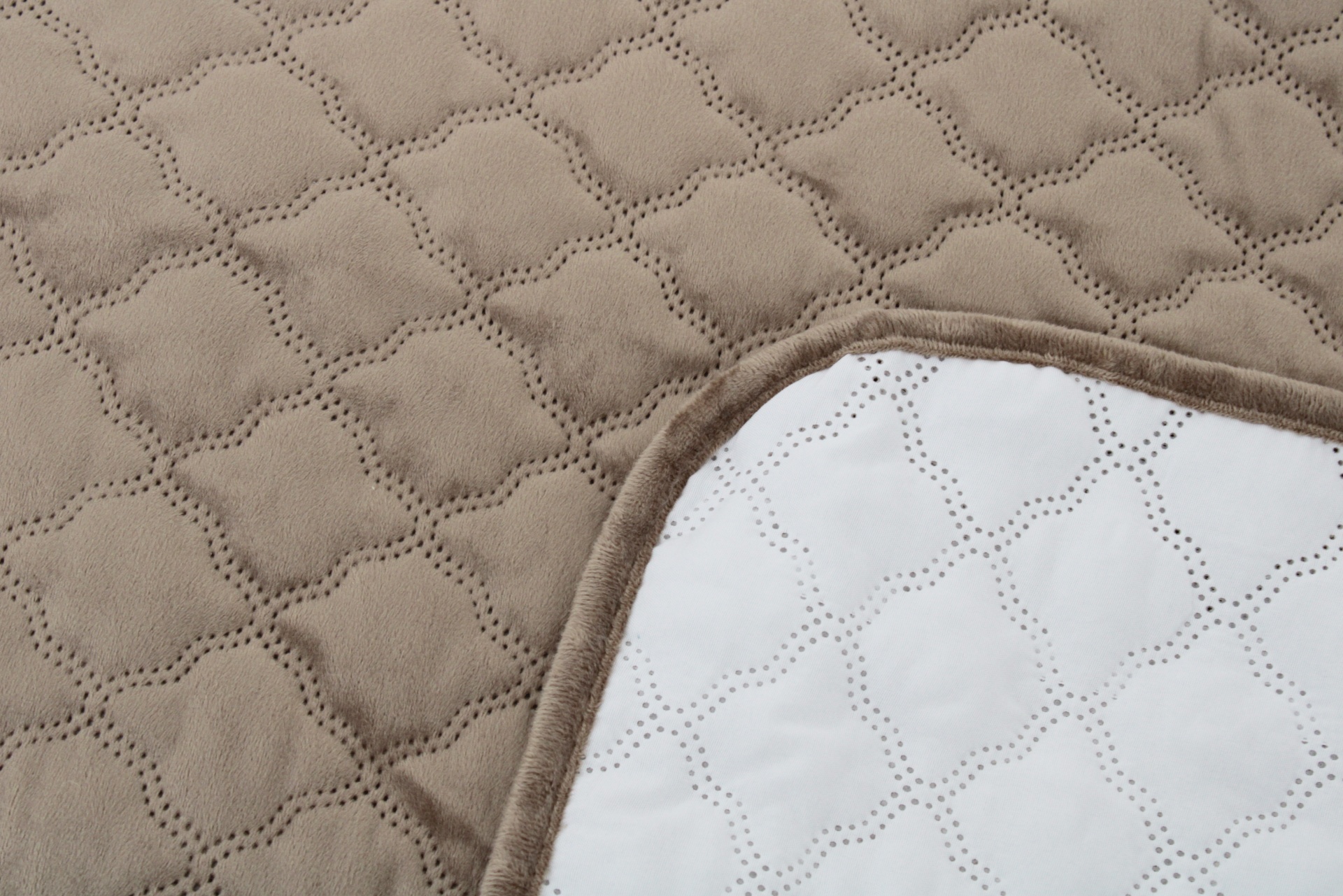 Manta acolchoada bege e branca com padrão geométrico e bordas castanhas