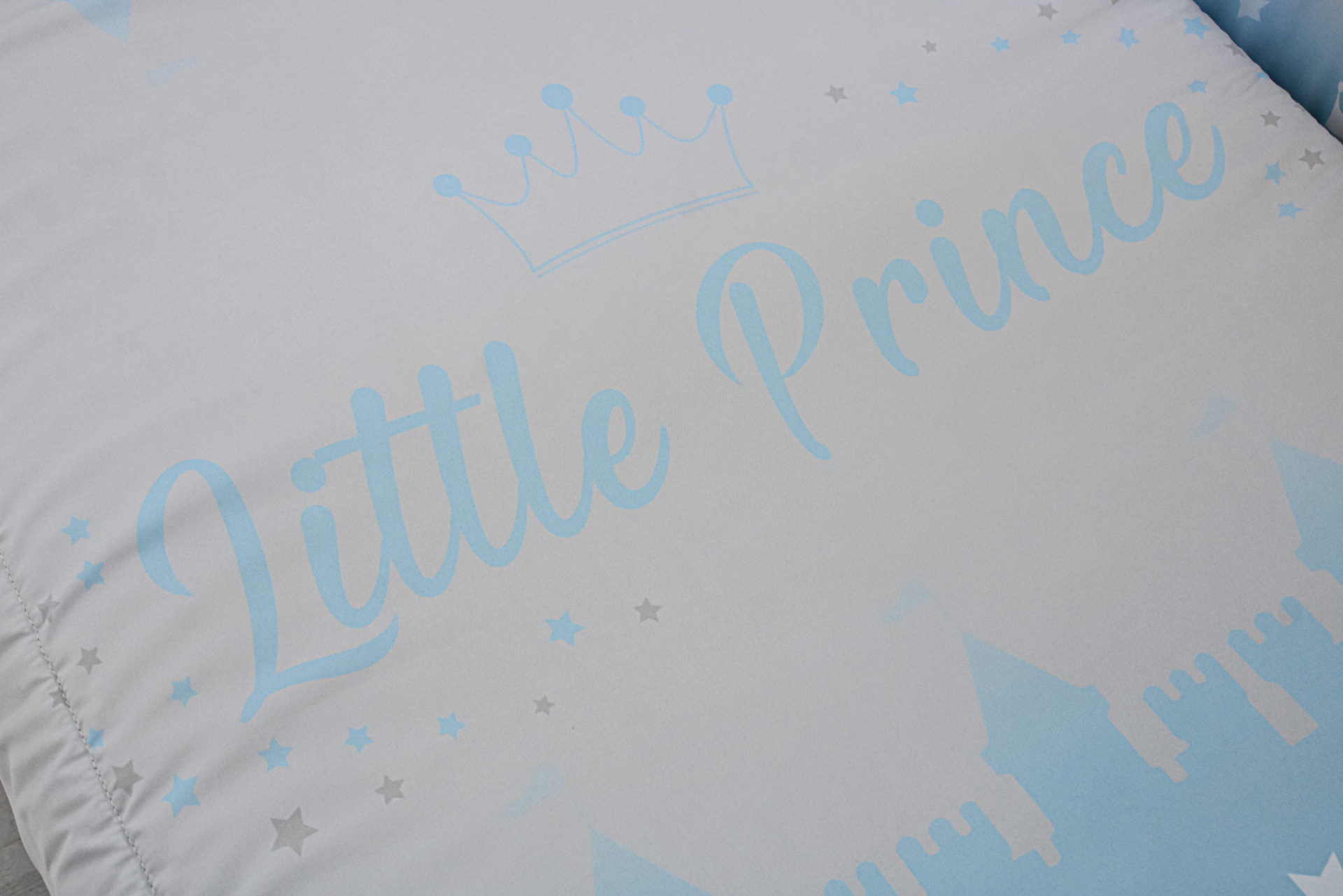 Colchão de bebé branco com texto azul 'Little Prince' e desenhos de coroas, estrelas e castelo.