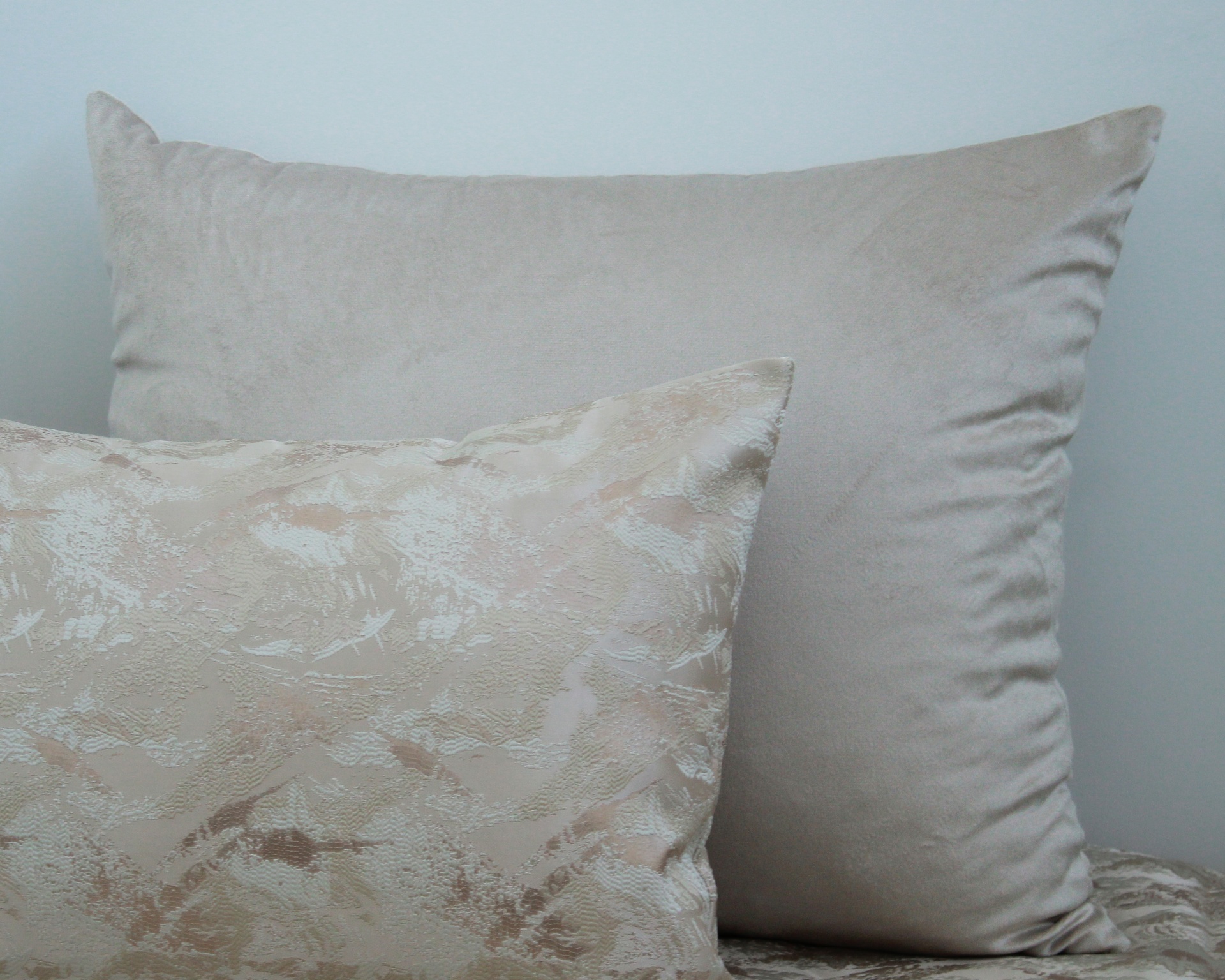 Duas almofadas, uma cinza clara lisa e outra bege com padrão texturizado