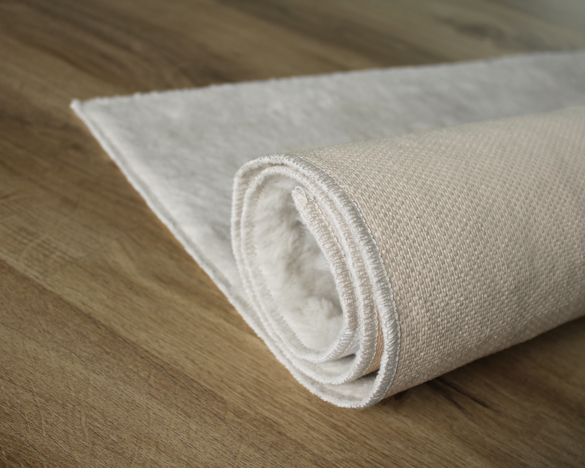 Tapete branco enrolado sobre chão de madeira