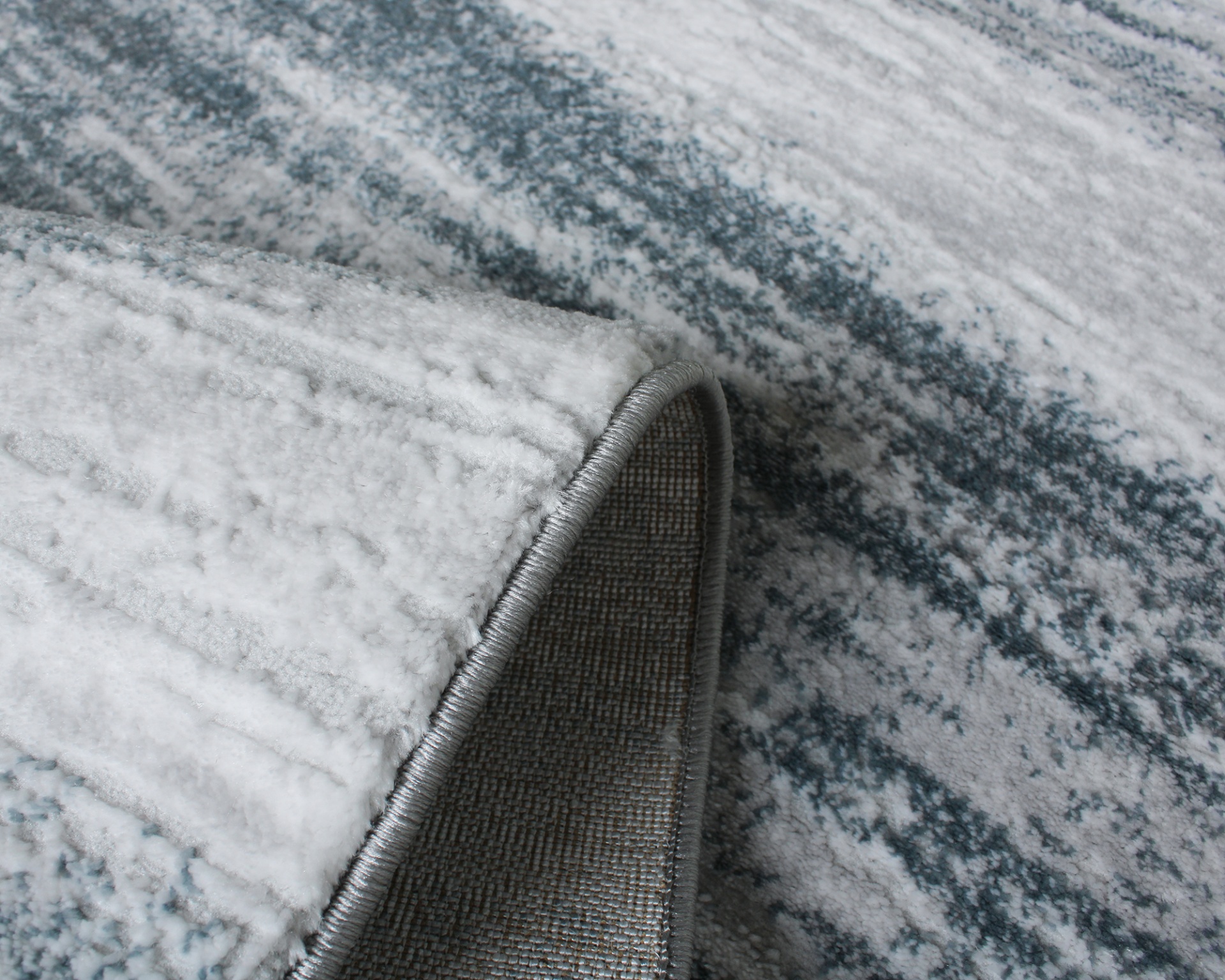 Tapete cinzento com padrão abstrato e borda costurada