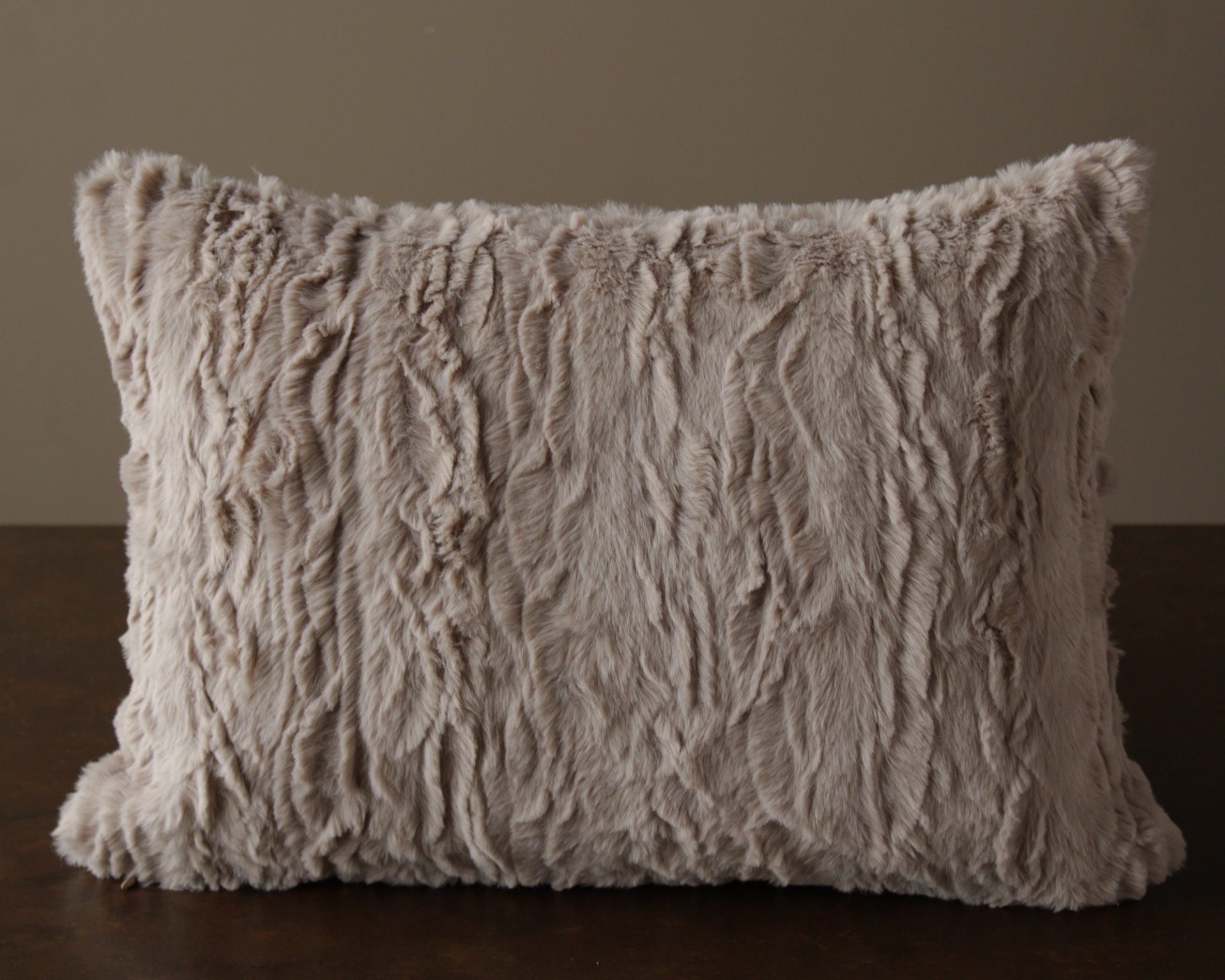 Almofada felpuda bege claro sobre superfície de madeira escura