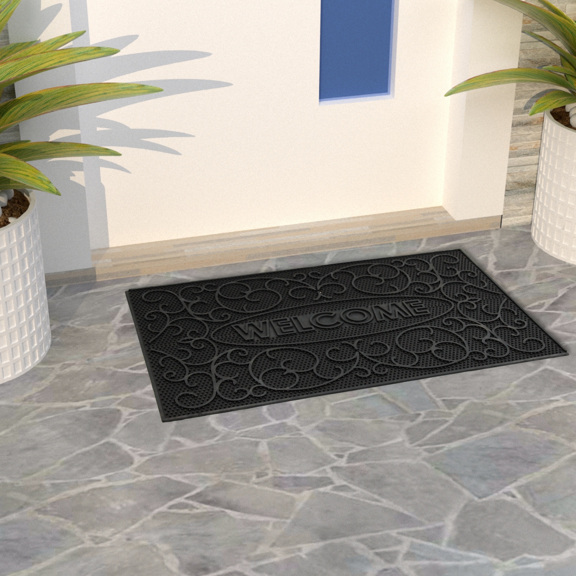 Tapete preto de boas-vindas com padrões em relevo num chão de pedra entre duas plantas em vasos brancos.