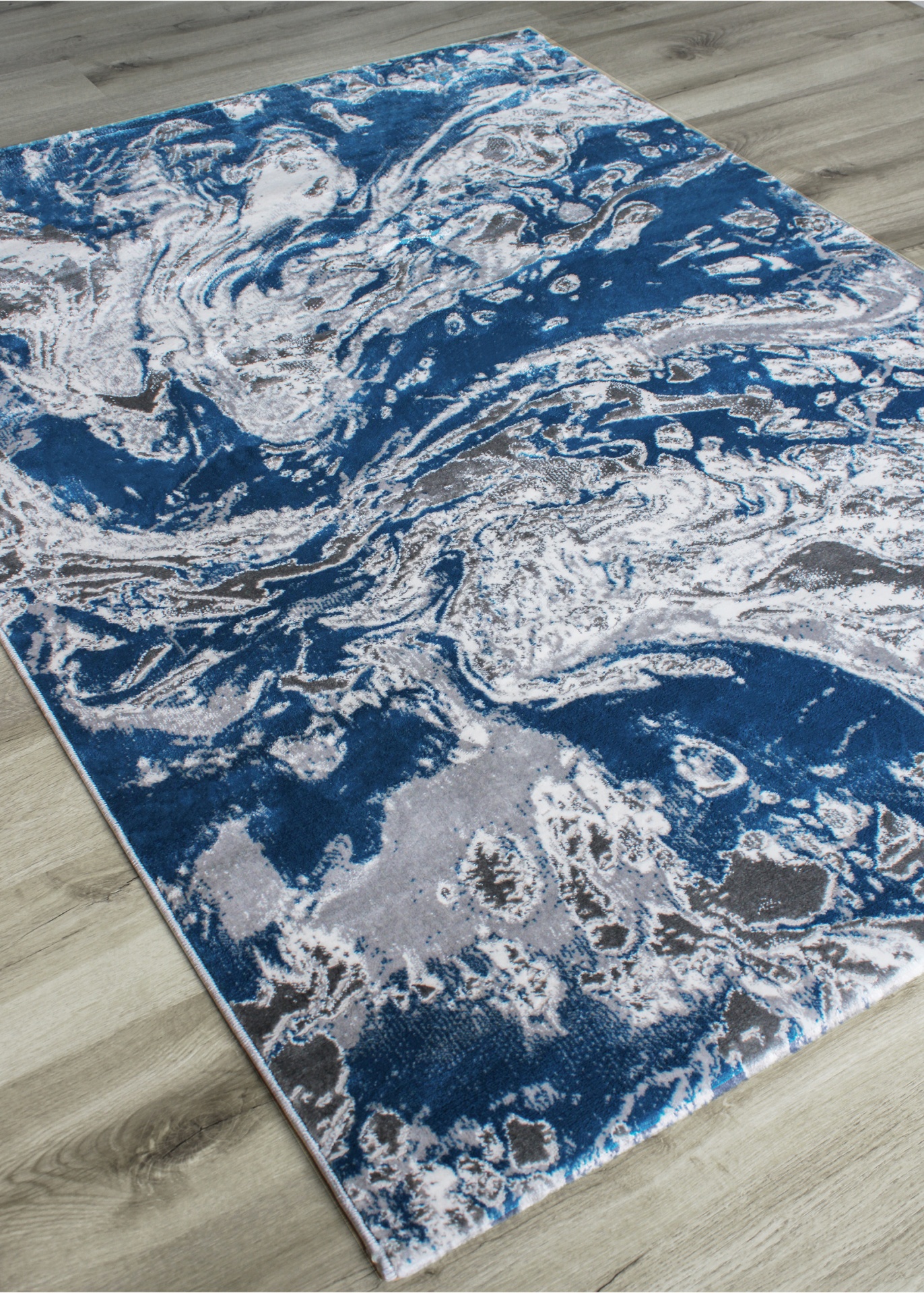 Tapete azul, branco e cinzento com padrão abstrato em chão de madeira clara