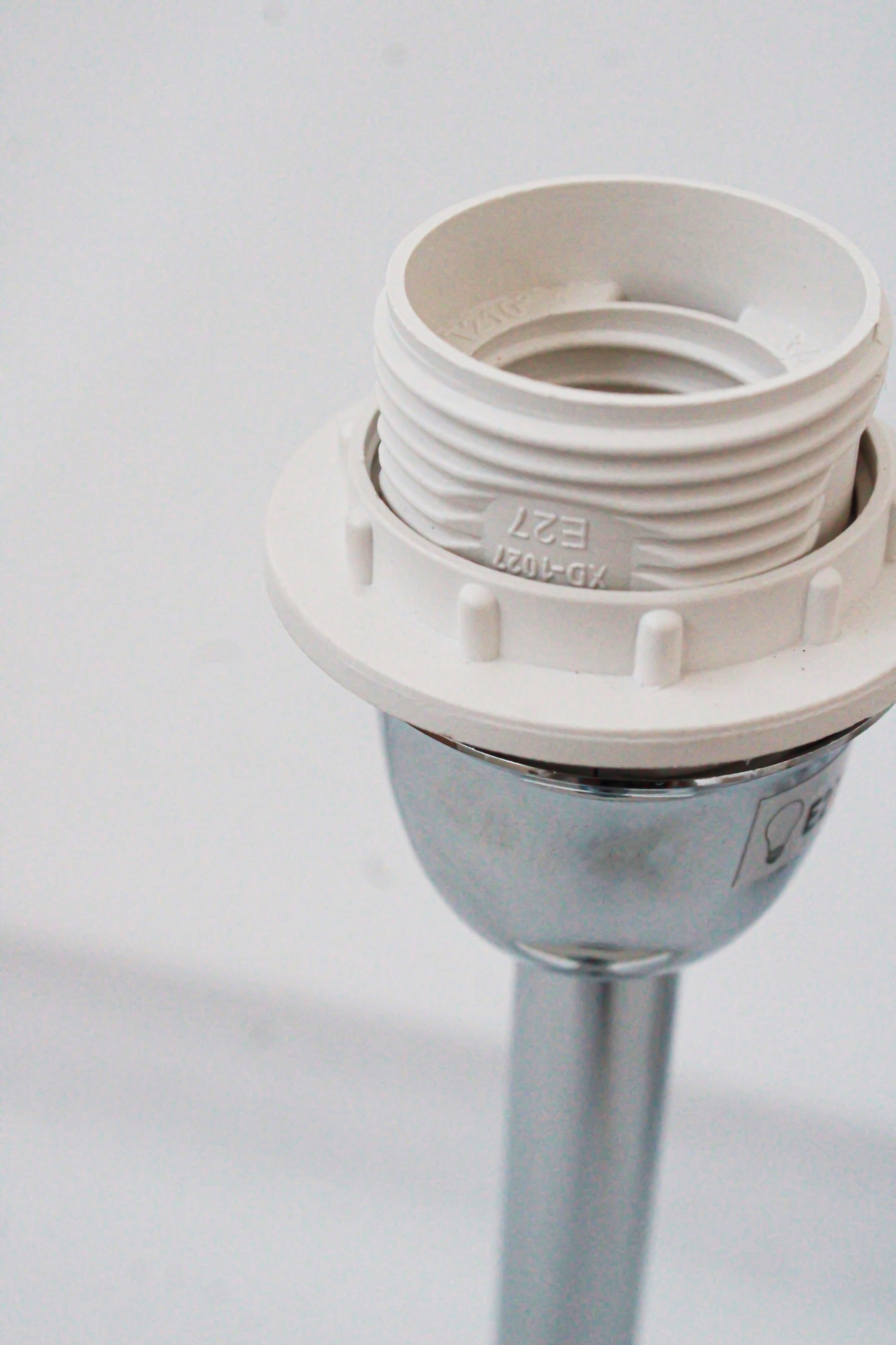 Peça metálica cromada com rosca de plástico branco e inscrições E27