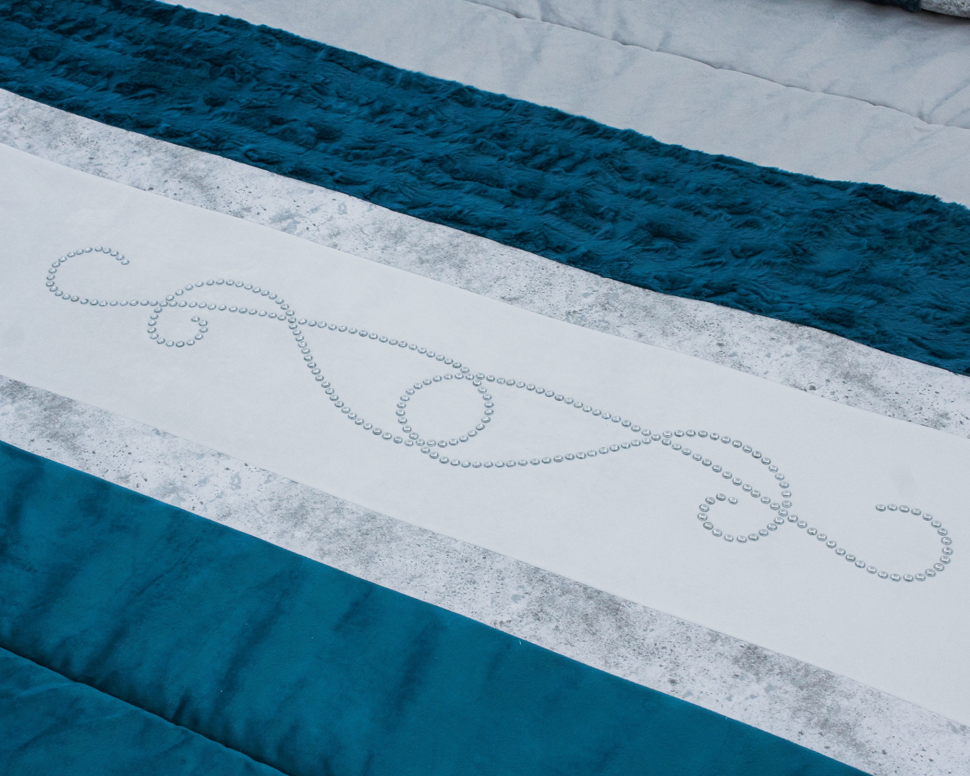 Colcha azul, cinzenta e branca com desenho de pérolas em espiral