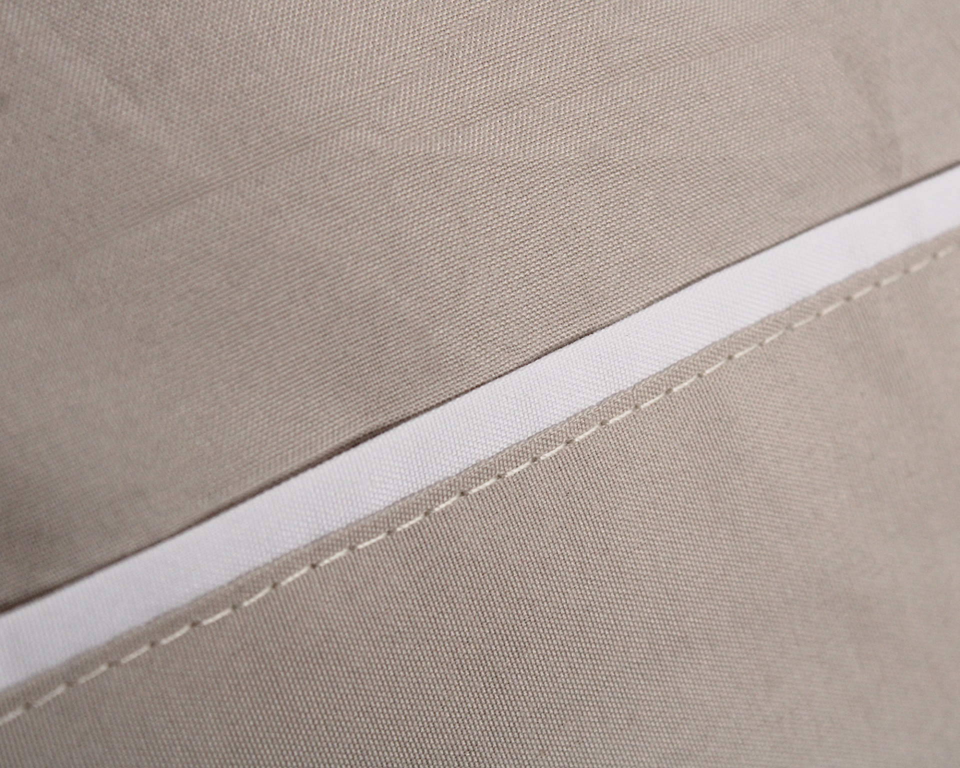 Close-up de tecido bege com costura branca e linha bege
