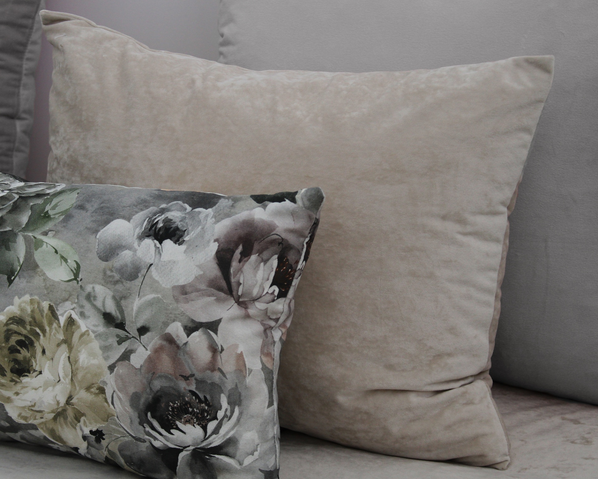 Almofadas decorativas cinza liso e floral sobre sofá cinza