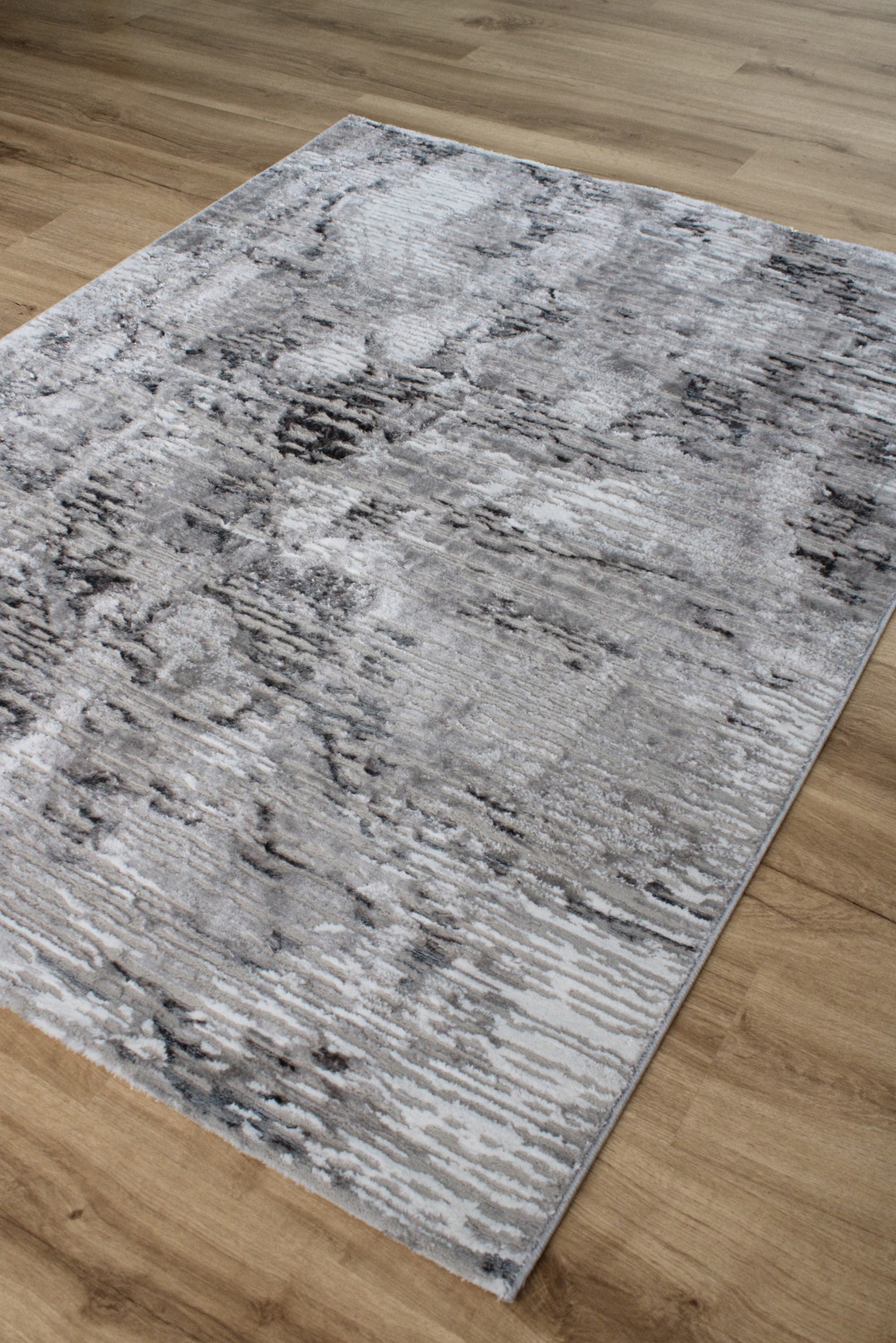 Tapete cinza com padrão abstrato colocado em chão de madeira clara