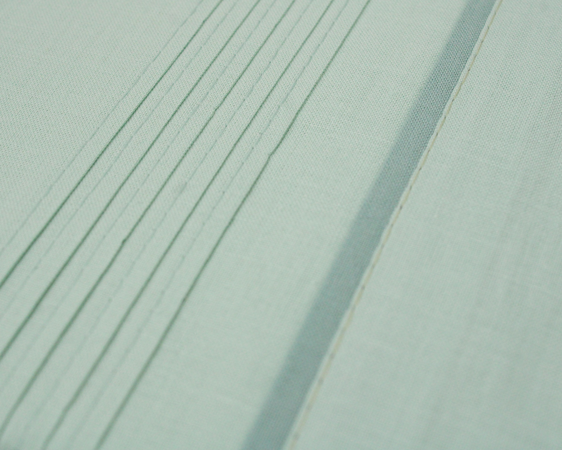 Tecido verde-água com linhas costuradas paralelas e texturas variadas