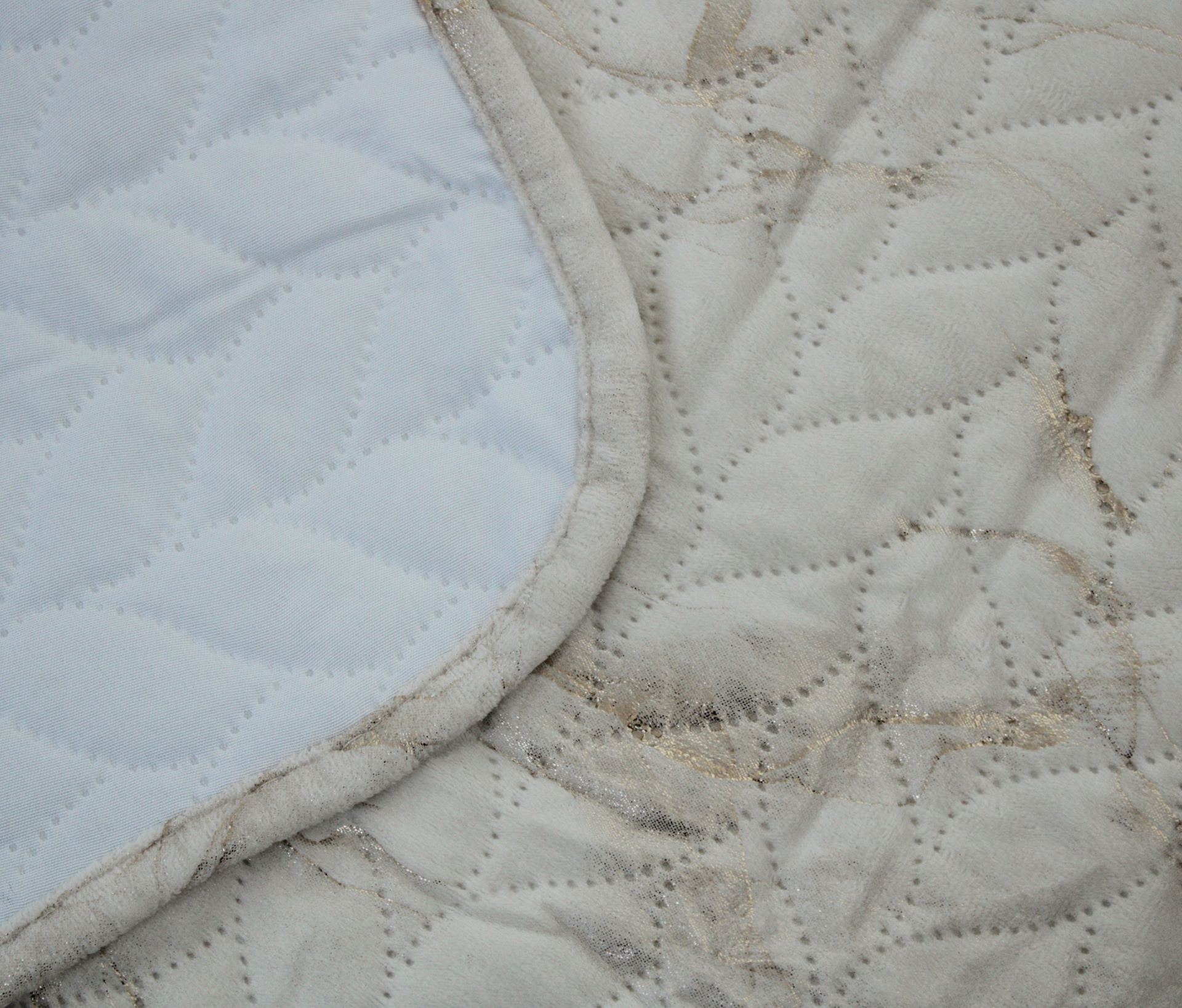 Duas mantas acolchoadas, branca e bege manchada, com padrão de folhas e bordas de tecido bege