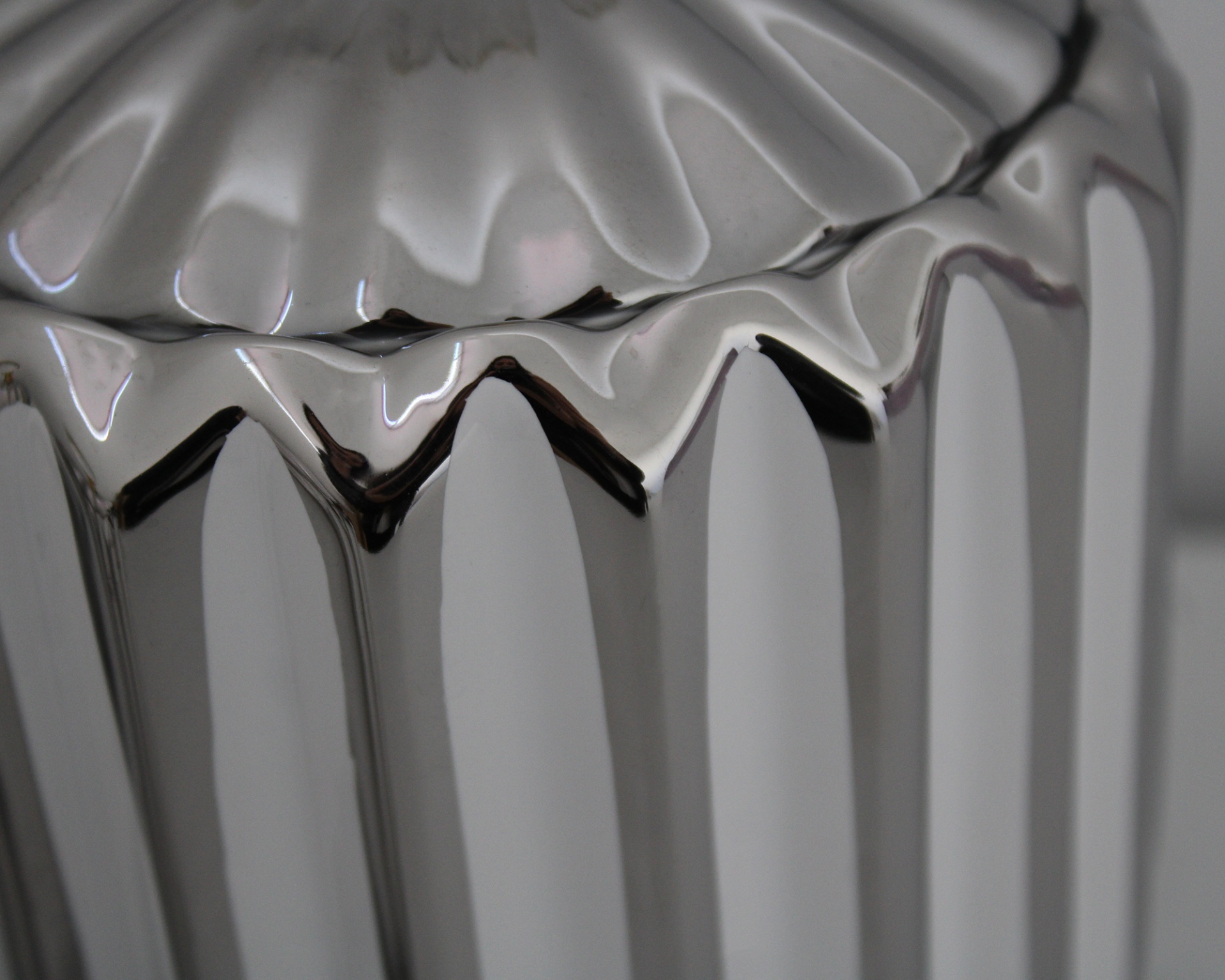 Recipiente metálico prateado com acabamento brilhante e textura canelada