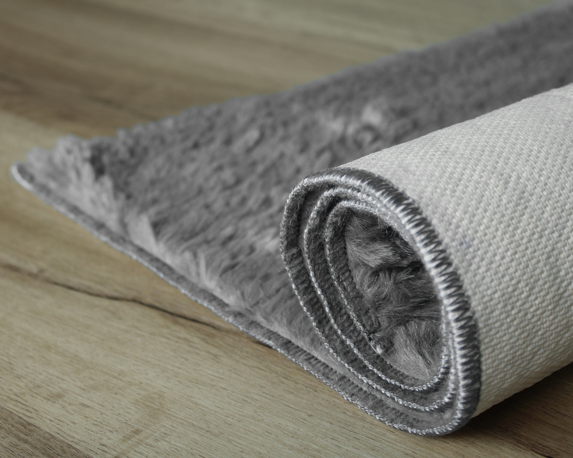 Tapete cinzento felpudo com verso branco e costura cinzenta