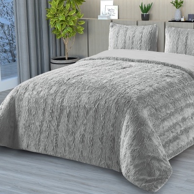 Cobertor e almofadas cinzentas com textura aveludada em cama moderna