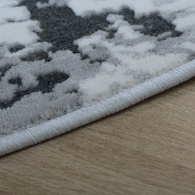 Tapete felpudo cinza e branco com padrão abstrato e borda romana