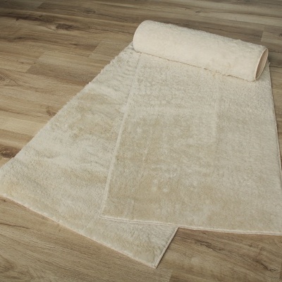 Tapete branco felpudo parcialmente enrolado sobre chão de madeira clara