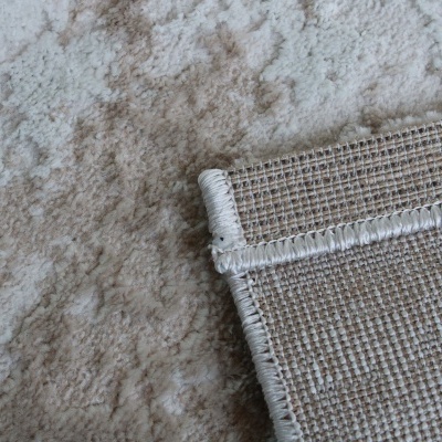 Detalhe de dois tapetes em tons bege e castanho, um macio e outro com trama visível