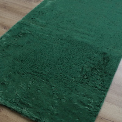 Tapete verde escuro de pelo macio sobre chão de madeira clara