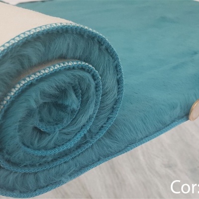 tapete ou manta turquesa com botão de madeira sobre piso claro