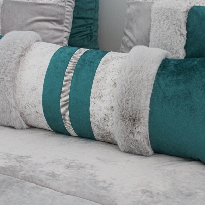 Almofada decorativa retangular verde e cinza com faixas em pêlo sintético em sofá cinza.