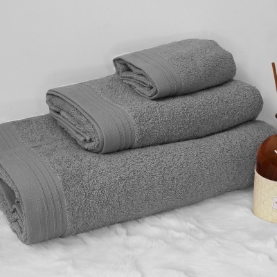 Três toalhas cinzentas empilhadas ao lado de frasco com difusor