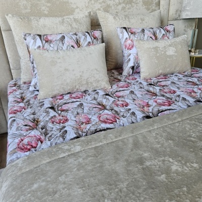 Roupa de cama com padrão floral e almofadas de veludo bege em cama com cabeceira estofada bege