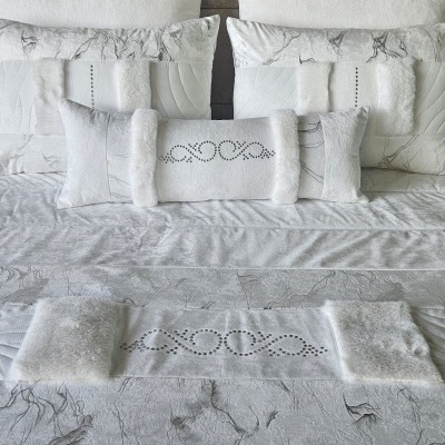 Conjunto de cama branco e cinzento com almofadas e colcha decoradas com cristais e detalhes em pelo
