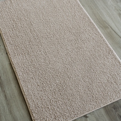 Tapete beige claro com textura macia sobre chão de madeira clara