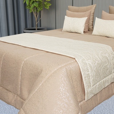 Colcha bege com detalhe acetinado e almofadas sobre cama em quarto moderno