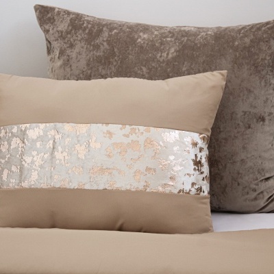 Duas almofadas decorativas, uma bege com faixa prateada e dourada e outra em veludo castanho