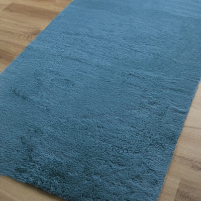 Tapete azul felpudo sobre chão de madeira