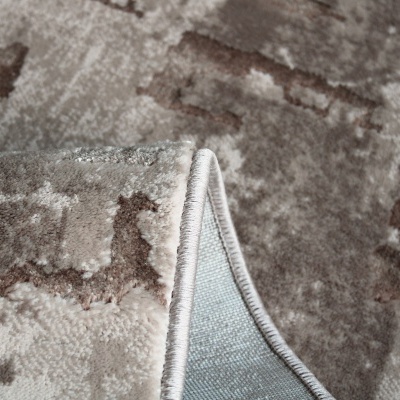Tapete felpudo bege com padrão abstrato e bordas costuradas.