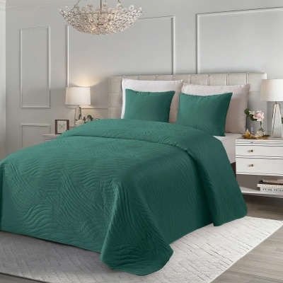 Colcha verde escura texturada num quarto moderno com cabeceira creme e candeeiros.