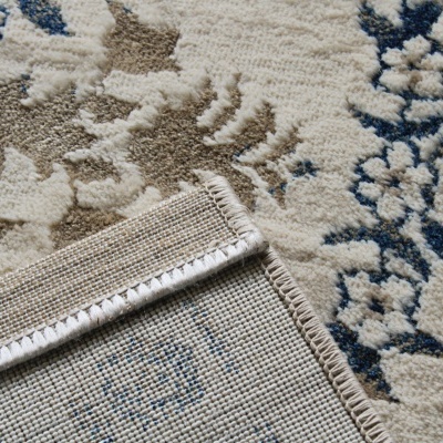 Tapete decorativo branco com padrão floral em azul e bege e bordas rematadas
