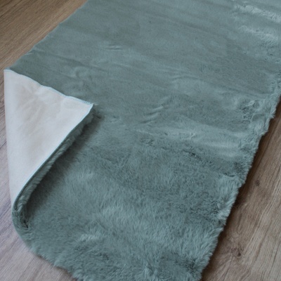 Tapete azul esverdeado felpudo sobre chão de madeira